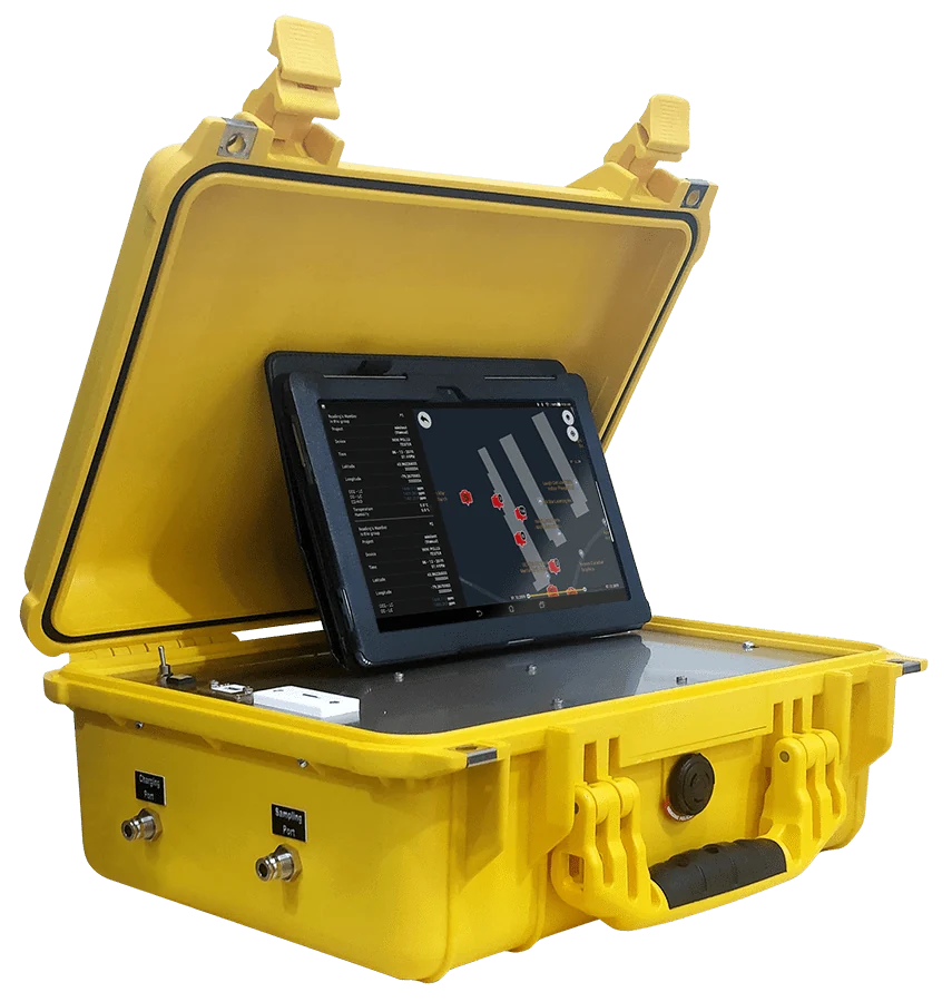 Saudi field technician carrying a TR8 OdoTracker along a wastewater-site route while the tablet displays two gas channels and GPS-tagged readings